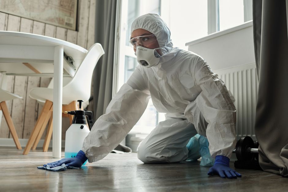 Certified technician in a protective suit performing a mold remediation service
